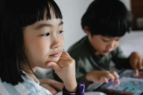 an image of two kids one think and the other one playing ipad